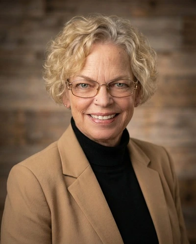 HeadshotPro AI-generated professional portrait of a smiling woman with glasses and blonde curly hair.