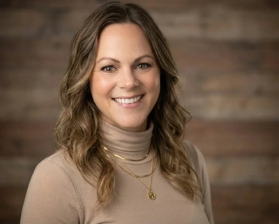 HeadshotPro output sample showing a professionally generated headshot of a smiling woman against a blurred wooden background.