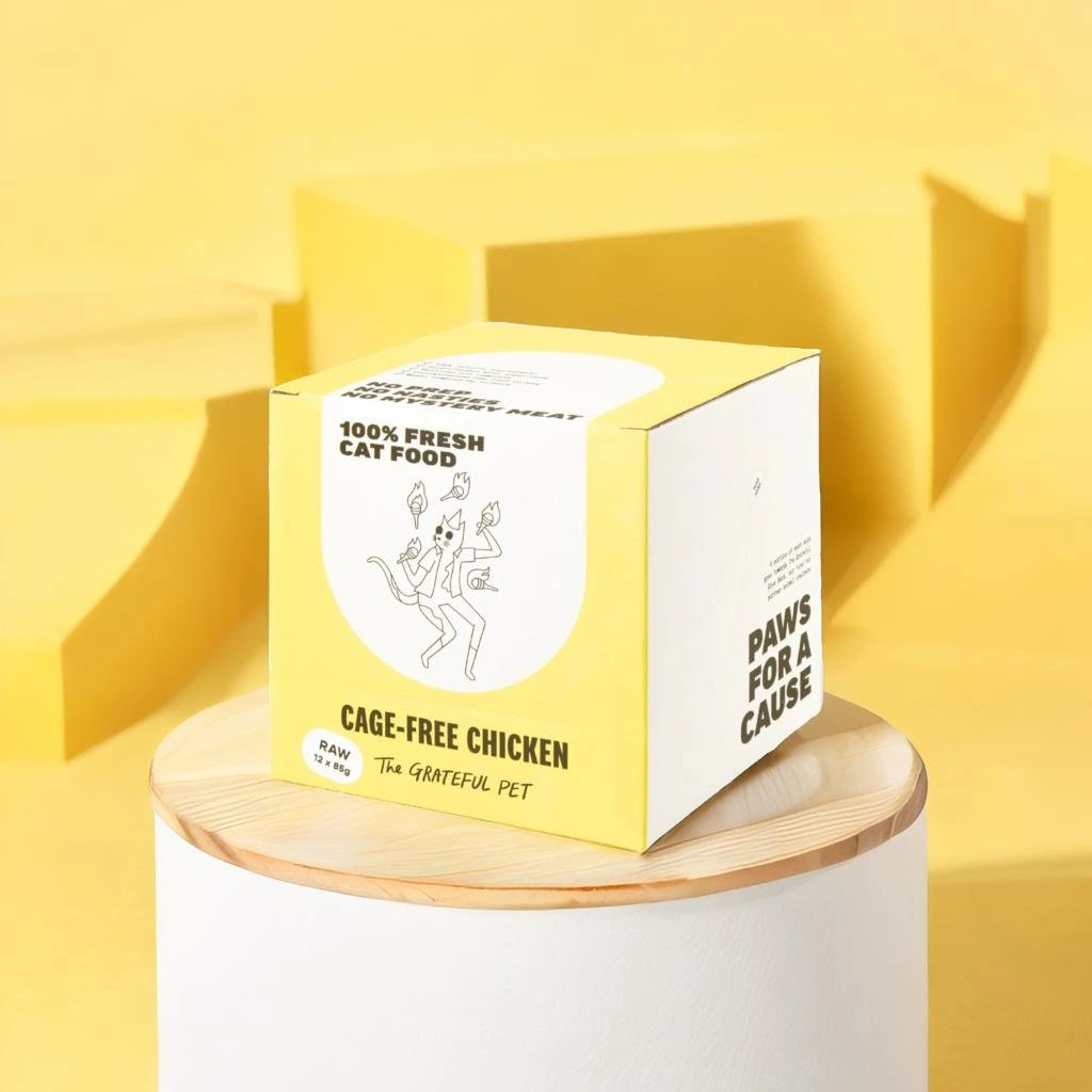 Pebblely output sample showing a modern pet food box on a minimalist yellow stage with warm shadows.