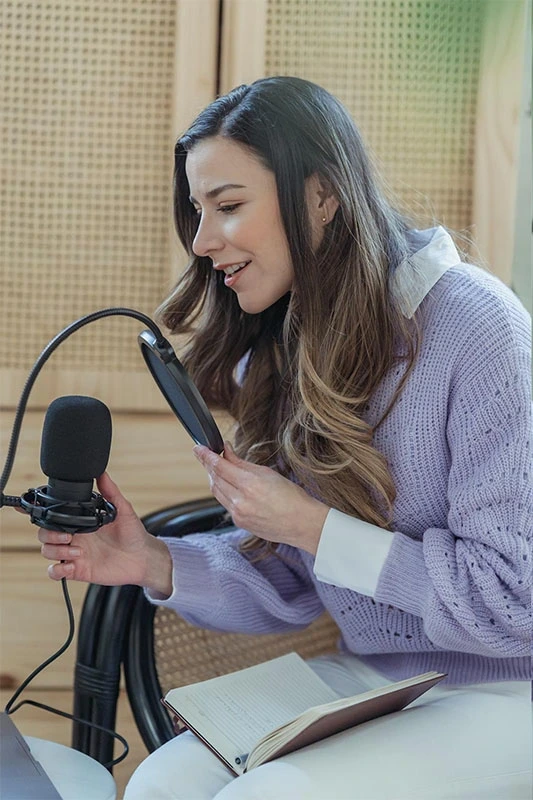 Podsqueeze user recording a podcast, speaking into a microphone with a pop filter.
