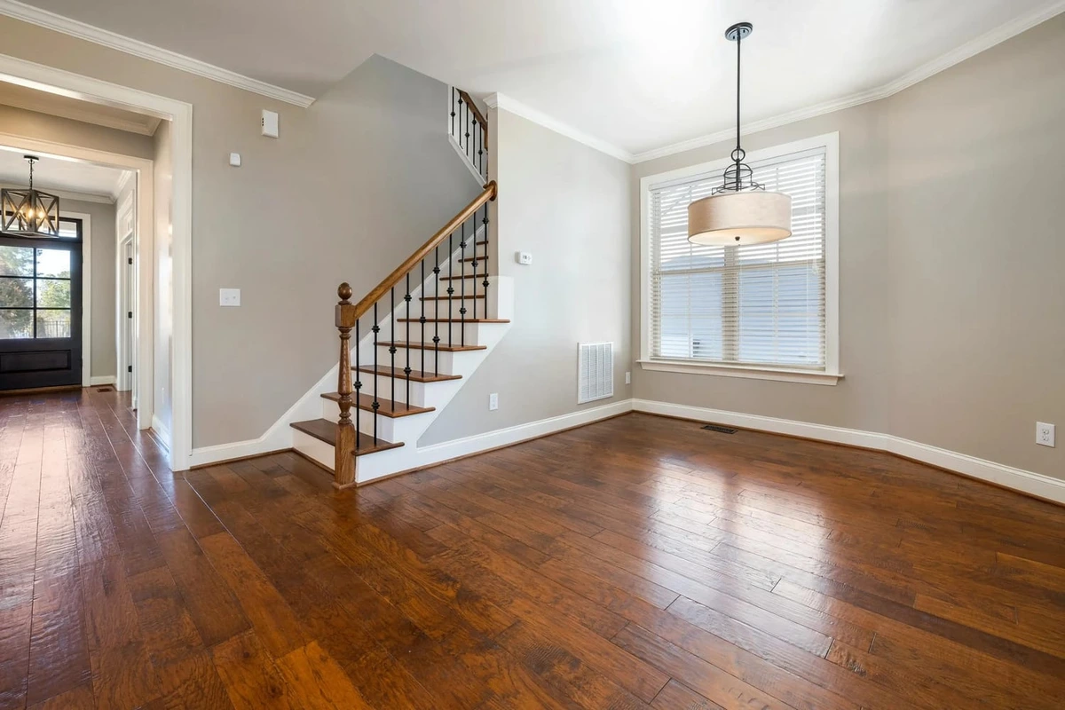 virtual-staging-ai before image of an empty room, showcasing a hardwood floor and staircase, ready for AI staging.